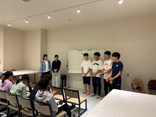 夜のミーティングでポスター発表をする様子